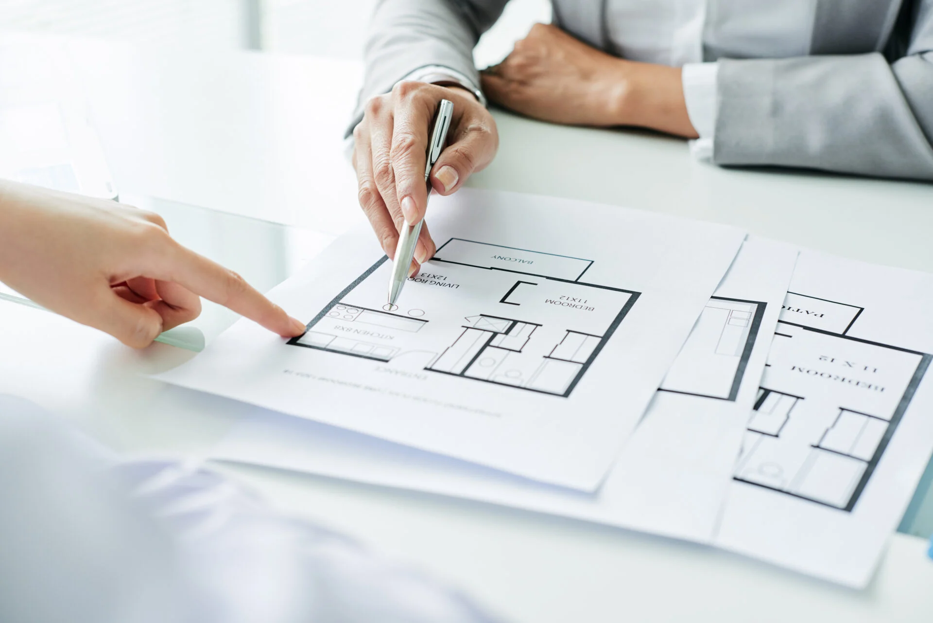 Person zeigt einen Architekturplan – Symbol für hochwertige Exposé-Erstellung zur optimalen Präsentation beim Immobilien-Verkauf für Eigentümer.